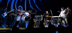 Dylan together with five members of his band onstage. Dylan, dressed in a white shirt and black pants, is second from right.