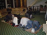 Line of men bending in Muslim prayers at a Pakistani home during Ramadan.