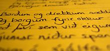 Photo of black handwritten text on a seemingly yellow paper with the top and bottom blurry and vertical middle clear