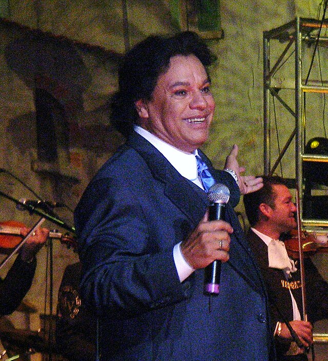 A man singing in a concert with arms wide open.