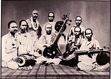 The Karaikudi Veena Brothers, from right to left: Karaikudi Sambasiva Iyer (veena), Karaikudi Subbarama Iyer (veena upright position) and Pudukkotai Dakshinamurthy Pillai (mridangam). 1917. Karaikudi Vina Brothers.jpg