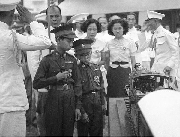 Thirteen year old King Ananda of Siam (left), and his brother Prince Bhumibol Adulyadej (right), inspect a model train presented to him at Saranrom Pa