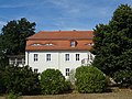 Western manor house (Lindenplatz 15), southwestern administrator's house (Lindenplatz 16), two farm buildings adjoining to the east (Lindenplatz 17 and 18) and two eastern barns (to No. 10) of the former manor and manor park (garden monument)