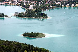 Die Kapuzinerinsel. Am gegenüberliegenden Ufer die Pörtschacher Halbinsel sowie links davon, nur teilweise sichtbar, die Schlangeninsel (Blumeninsel)