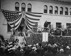 Theodore Roosevelt speaking on platform in front of Pearsons Hall to dense crowd