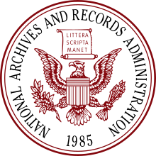 Circular seal with the coat of arms of the United States in the centre: A bald eagle supporting a shield resembling the United States flag, with its wings outstretched, 13 arrows in its left talonand an olive branch in its right talon. A scroll above the eagle reads "Littera Scripta Manet" (meaning "the written word lasts"). Around the inner edge of the seal are the words "National Archives and Records Administration" and, at the lowest point, the year 1985.