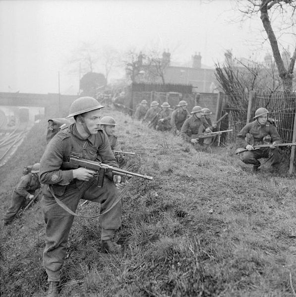 Infantry training at the division's battle school. The troops are seen advancing between the backs of houses along a railway line.