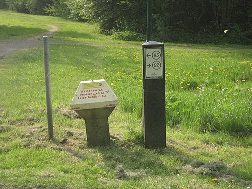 Un panneau d'entre-nœud à côté d'un "panneau-tabouret" qui donne les noms locaux et les distances. Les deux sont utilisés ensemble aux Pays-Bas.