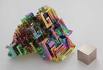 Cristal artificiel de bismuth métallique et cube d'un centimètre cube de bismuth (99,99 %). L'irisation est due à une couche d'oxyde très mince. (définition réelle 5 176 × 3 519)
