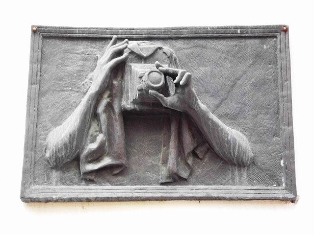 sculpture of someone holding an old camera