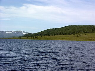 le lac avec une forêt et la chaîne d'Aigoulak au fond.