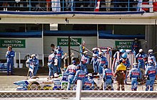 Foto de un stand de los mecánicos trabajando en un coche.