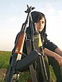 A YPJ fighter sits next to stacked rifles.jpg