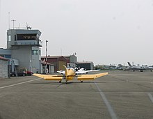 Et fly på en landingsbane med et kontroltårn.