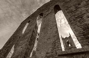 Schwarz-Weiß-Fotografie eines Kirchturms aus einem niedrigen Winkel durch Lanzettenfenster gesehen.