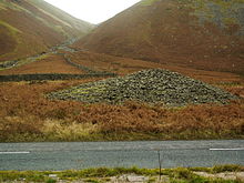 The cairn of Dunmail Raise lying between the dual carriageways of the A591 road. Cairn of Dunmail Raise.JPG