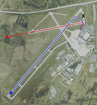 Letecký snímek letiště Blue Grass v Kentucky v roce 2002 s červenou šipkou a modrou šipkou označující cesty na obou drahách.