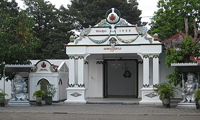 Front of white building, with two statues in front