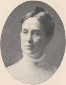 A yearbook photograph of a middle-aged white woman, hair parted center and dressed up and back; she is wearing a shirtwaist with a high lace collar