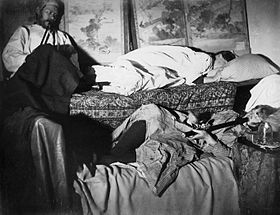 Two women and a man smoking in an opium den, late 19th century Opium den chinatown.jpg