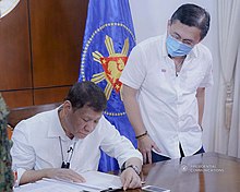 President Rodrigo Duterte (seated) signs into law the establishment of the National Academy of Sports in Panacan, Davao City on June 9, 2020. President Rodrigo Roa Duterte signs into law the establishment of the National Academy of Sports 04.jpg