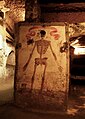 Un dipinto, con teschio incassato, tra i cunicoli delle catacombe.