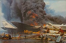 Aircraft burning on the flight deck. In the foreground crewmen move AGM-45 Shrike missiles away from the conflagration. USS Forrestal fire RA-5Cs burning 1967.jpg