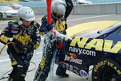 Fuel spills from the gas tank as pit crew members in their PPE