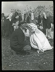 un anthropologue et un danseur masqué face à face vers 1900