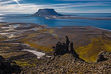 En rullesteinstrand ved sjøen, med Bell Island i bakgrunnen