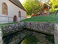 Das sog. „Heilbad“ neben der Kapelle. Das Quellwasser fließt unter der Steinbank in das Bad hinein.