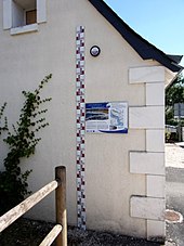 Photographie en couleurs représentant une règle graduée le long d'un mur avec des repères de hauteur et des dates.