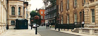 Downing Street looking west. The Foreign and Commonwealth Office is on the left. The three adjoining houses 9-11 Downing St. are of dark brick, 11 having a white stucco ground floor. 12 Downing Street is the later-built red-brick building projecting forward from the line of the other three. The building on the near right is the Barry wing of the Cabinet Office, which has its main frontage on Whitehall. Downing Street.jpg