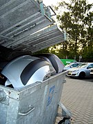 Poubelle d'un atelier automobile, contenant des objets potentiellement de grande valeur.