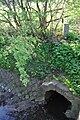 Grenzstein an der Osterbek, die hier die ehemaligen Grenze des Amtes Trittau und der Hamburger Exklave Farmsen und die heutigen Grenze der Hamburger Stadtteile Bramfeld und Farmsen-Berne bildet. Der Grenzstein liegt auf Bramfelder Seite an der Brücke Tegelweg. Inschrift: 11 / AT / 1855 (Grenzstein 12, Amt Trittau, gesetzt 1855)