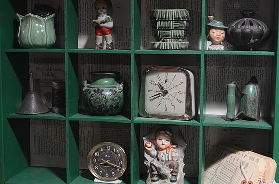 Objects (hundred year old figurines, clocks, and jars) inside a Pigeon-hole cabinet