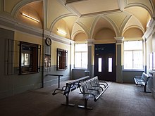 Pohled do typické současné čekárny ve stanici ATE, na litoměřickém horním nádraží. Dominuje jí strop s klenbami a řada laviček pro čekání cestujících. Na levé straně se pak nacházejí dvě okna osobních pokladen.