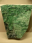 Jade plaque of a Maya king; 400-800 (Classic period); height: 14 cm, width: 14 cm; found at Teotihuacan; British Museum (London). On this plaque is represented a Maya ruler in full ceremonial regalia sitting cross-legged on a throne. His head is shown in profile, while his body faces to the front. He wears an elaborate plumed headdress incorporating part of the head of a monstrous animal. He is richly decorated with personal ornaments, many of which would have been made of jade. These include ear flares, a bar pectoral, wristlets, anklets and an impressive belt with a mask