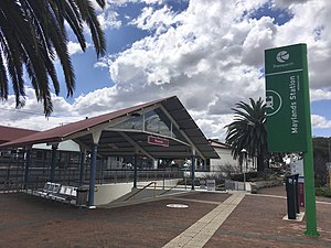 An entrance with a staircase down to a pedestrian underpass, with the station platform behind