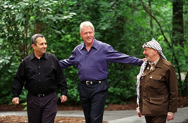 President Clinton walks with Prime Minister Ehud Barak of Israel and Yasser Arafat of the Palestinian Authority on the grounds of Camp David