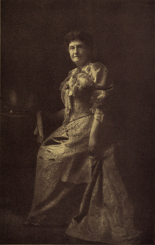 B&W portrait photo of a woman wearing a long, formal dress.