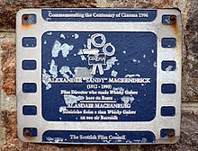 Castlebay auf der Insel Barra, Äußere Hebriden: Gedenkplakette des Scottish Film Council von 1996 für Regisseur Alexander „Sandy“ Mackendrick, der hier 1949 den Film Whisky Galore! drehte. Die Plakette ist zweisprachig in Englisch und Gälisch.