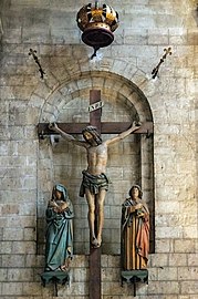 Crocifissione davanti ad un'apertura murata che conduce al portale occidentale murato. La croce è fissata in un'alcova del muro dell'architrave romanico.