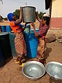 A lady assisting her friend to carry water on the head in Northern Ghana 03