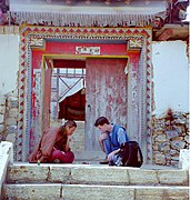 Buddhist monk and American tourist playing checkers in front of a monastery gate, Zhongdian, now Shangri-La, October 1999