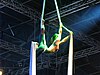 A young performer on two aerial silks against a dark background