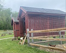 Two small red corn cribs at Fosterfields, New Jersey, likely built c. 1900 Cat and goats and chickens.jpg