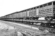 A train of coupled Commonwealth Railways narrow-gauge cattle cars on continuous rails laid on standard gauge flatcars (outback Australia) Commonwealth Railways narrow-gauge cattle cars on rails laid on standard-gauge flatcars, Stirling North-Marree line, 1955.jpg