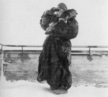 A woman dressed in thick fur using binoculars.