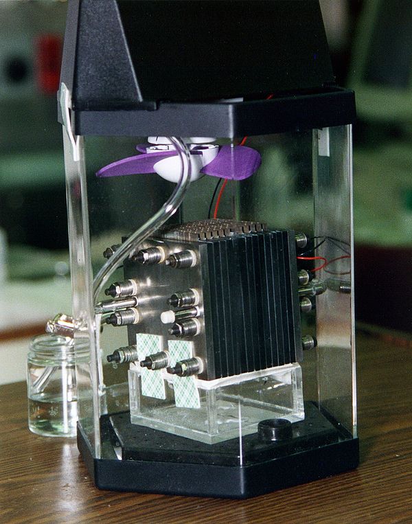 Demonstration model of a direct methanol fuel cell (black layered cube) in its enclosure.